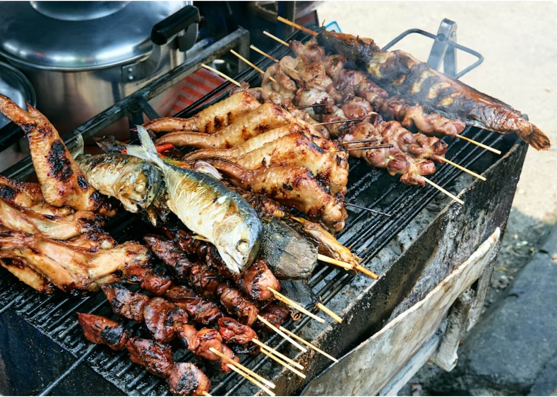 Grilled fish and meat skewers on a charcoal grill